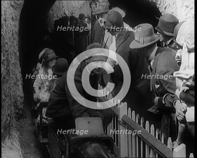 A Model Train Passes Through a Tunnel As a Crowd of People Watch from Behind a Fence, 1924. Creator: British Pathe Ltd.