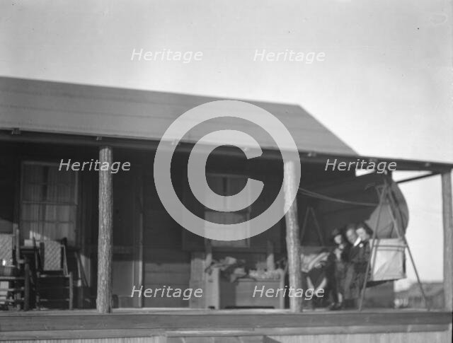 Arnold Genthe and two women friends seated on a swing on the porch of his...New York, c1911-c1942. Creator: Arnold Genthe.