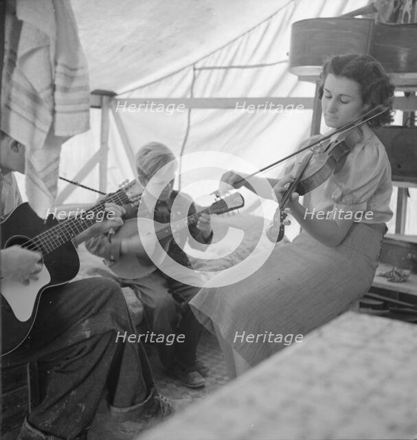 Migrant family from Arkansas playing hill-billy songs, FSA...migratory camp, Calipatria, CA, 1939. Creator: Dorothea Lange.