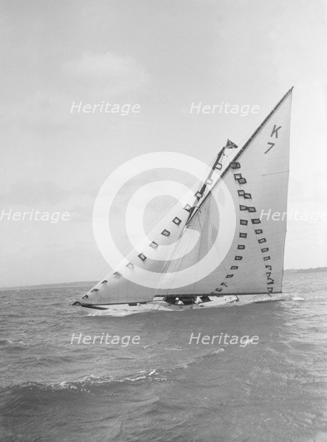 The 7 Metre 'Ginerva' (K7) under sail with prize flags, 1912. Creator: Kirk & Sons of Cowes.