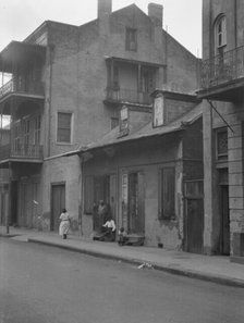 View from across street of a man and child sitting on steps and a woman walking down..., c1920-1926. Creator: Arnold Genthe.