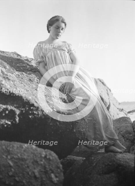 Wilson, Helen, Mrs., seated on rocks at the beach, between 1906 and 1928. Creator: Arnold Genthe.