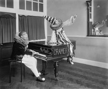 Two Pierrot clowns performing a routine with a piano, 1917. Artist: Bedford Lemere and Company.