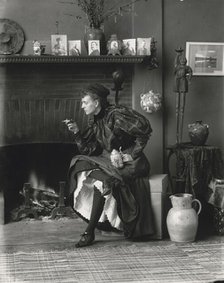 Frances Benjamin Johnston, full-length portrait, seated in front of fireplace, facing left..., 1896. Creator: Frances Benjamin Johnston.