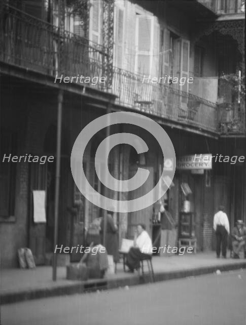 View from across street of people under a covered sidewalk, New Orleans, between 1920 and 1926. Creator: Arnold Genthe.