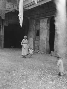 Woman and children in a courtyard, New Orleans, between 1920 and 1926. Creator: Arnold Genthe.