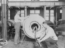 Three men working on large gun in Naval Gun Factory, Washington, D.C., one of the men lying..., 1903 Creator: Frances Benjamin Johnston.