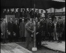 Two British Men Guiding a Time Capsule Being Lowered in the Ground With Various Civilians..., 1938. Creator: British Pathe Ltd.