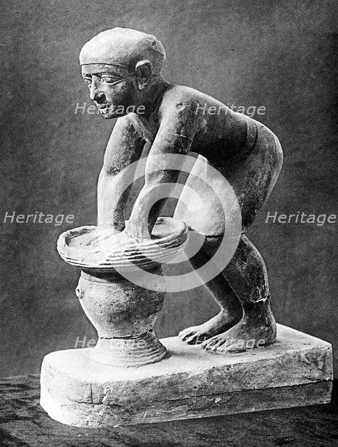 Figure of an Ancient Egyptian brewer pressing out fermented bread in a basket, c1910. Artist: Unknown