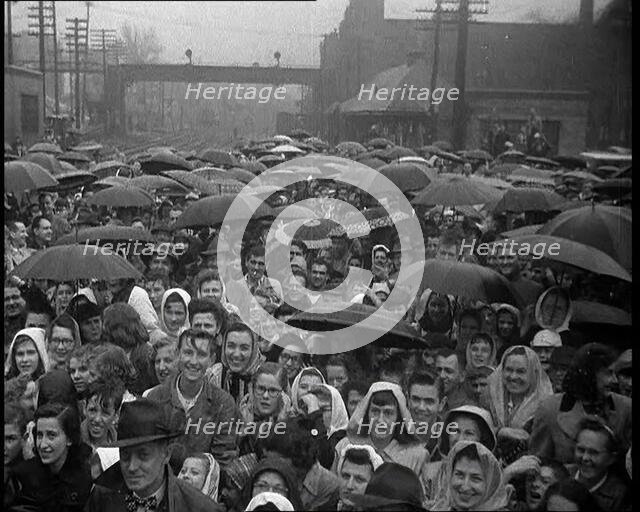Masses of People Cheering the Train As It Passes By Many Have Umbrellas As It Is Raining, 1932. Creator: British Pathe Ltd.