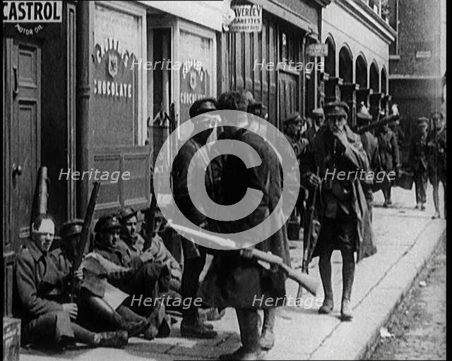 Irish Soldiers Sitting in the Street and Tending to Their Injuries from Fighting in Dublin, 1922. Creator: British Pathe Ltd.