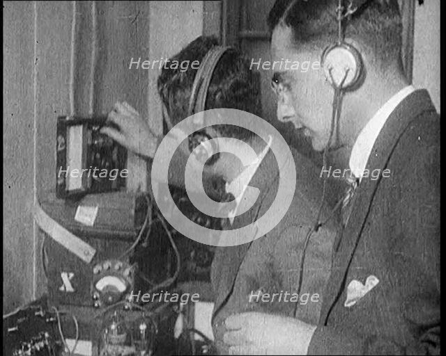 Two Men Wearing Headphones and Calibrating Wireless Equipment, 1922. Creator: British Pathe Ltd.