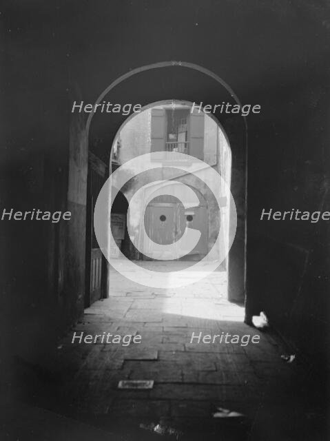View of a courtyard through an arched passageway, New Orleans, between 1920 and 1926. Creator: Arnold Genthe.