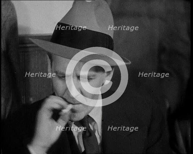 Male American Civilian Smoking a Cigarette While Reporting from the Courtroom During the..., 1930s. Creator: British Pathe Ltd.
