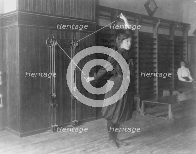 Female student exercising with a wall-mounted device using ropes and..., Washington, DC, (1899?). Creator: Frances Benjamin Johnston.
