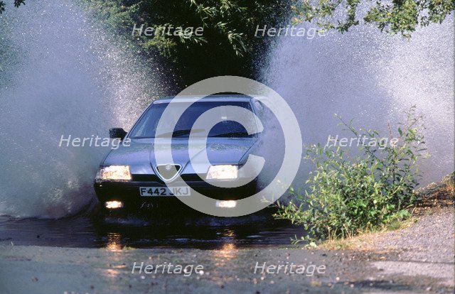 1989 Alfa Romeo 164 driving through a ford. Artist: Unknown.
