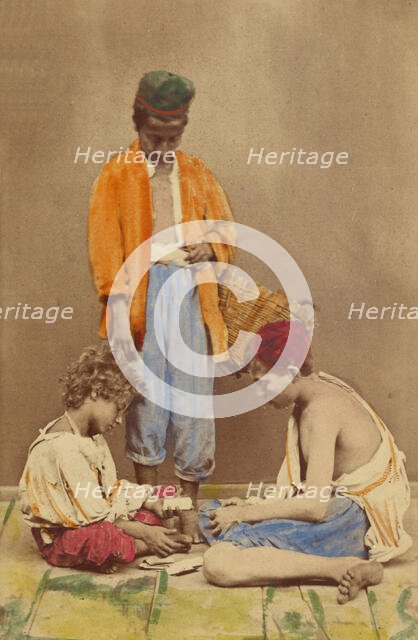 Unidentified man with basket standing, plus two boys seated playing cards, 1865-1870. Creator: Giorgio Conrad.