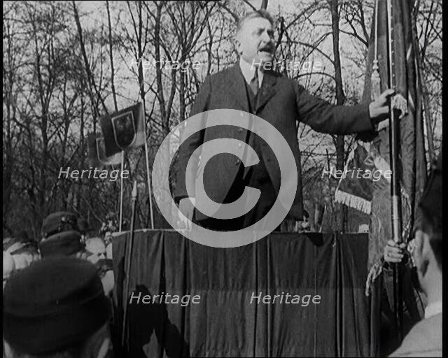 A Male Civilian Makes a Speech from a Stand in Front of a Crowd of Male Civilians Carrying..., 1924. Creator: British Pathe Ltd.