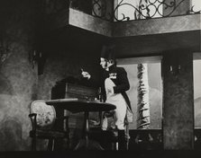 Man standing by table, 1938. Creator: Unknown.