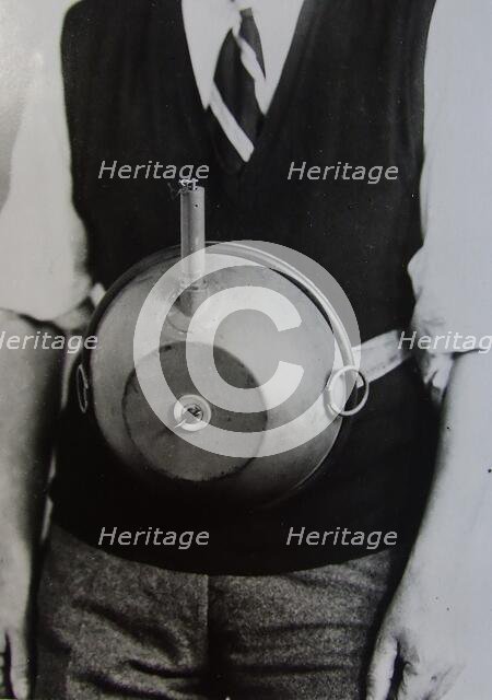 Cecil Vandepeer Clarke wearing an early version of the limpet mine on a keeper plate, c1939.  Creator: British Government.