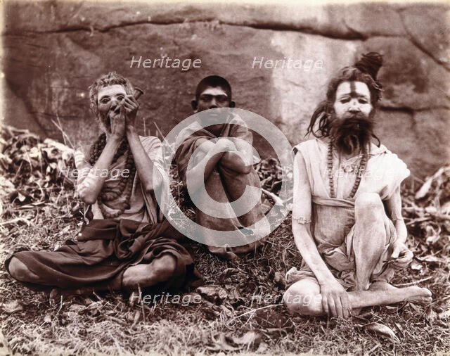 Two men and a boy sitting cross-legged on the ground surrounded by leaves; their faces...  1896/1897 Creator: Unknown.