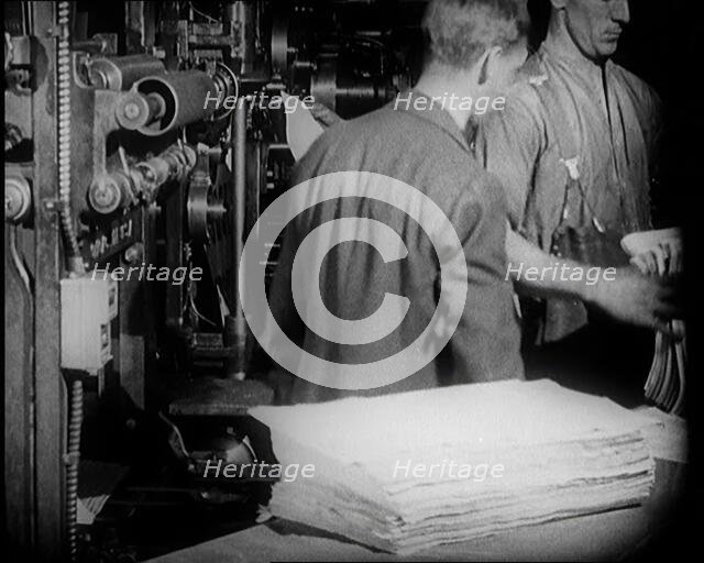 Male Printers Pulling Newspapers Off the Printing Press, 1921. Creator: British Pathe Ltd.