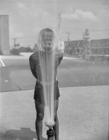 Playing in the community sprayer, Frederick Douglass housing project, Anacostia, D.C., 1942. Creator: Gordon Parks.