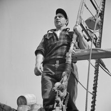 Gloucester fisherman standing in the rigging of a New England fishing boat, New York, 1943. Creator: Gordon Parks.