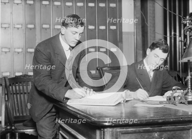 Two new citizens sign naturalizaton papers in judge's chambers, 1910. Creator: Bain News Service.
