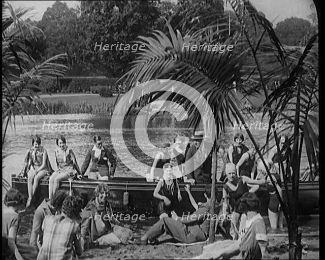 A Group of Young Civilians Wearing Swimsuits Seating on a Boat on Riverside, 1920. Creator: British Pathe Ltd.