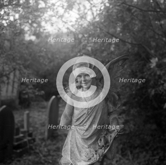 Statue of a child angel with a missing arm, Highgate Cemetery, Hampstead, London, 1987. Artist: John Gay.