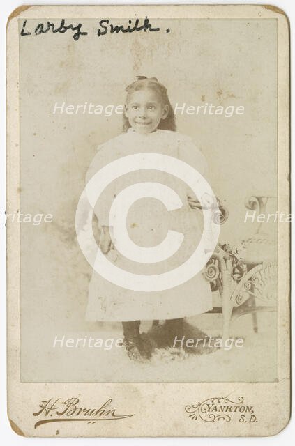 Photograph of Larby Smith standing next to a wicker chair., late 19th century. Creator: Henry Bruhn.