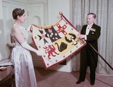 The Australian High Commissioner to Britain and his wife holding the standard of Australia, 1953. Creator: Arthur Charles Kirby Ware.