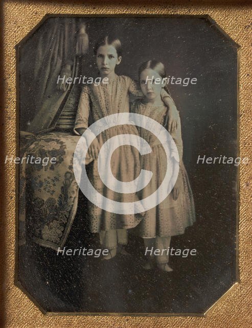 Two Identically Dressed Young Girls Standing Next to a Table, 1840s. Creator: Unknown.