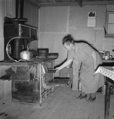 Mrs. Wardlow baking corn bread in her dugout basement home, Dead Ox Flat, Oregon, 1939. Creator: Dorothea Lange.