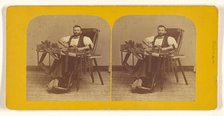 Portrait of Charles H. Barnes, Hardwick, Mass. seated in handicapped-style chair making ..., 1870s. Creator: George T Putnam.