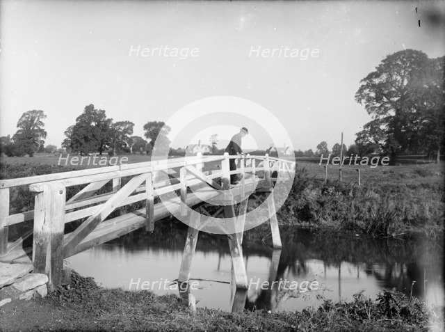 A man looking over the Eisey Footbridge into the River Thames, Cricklade, Wiltshire, c1860-c1922. Artist: Henry Taunt