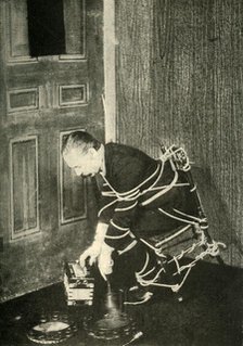 John Nevil Maskelyne performs a 'spirit cabinet illusion', c1910. Creator: Unknown.