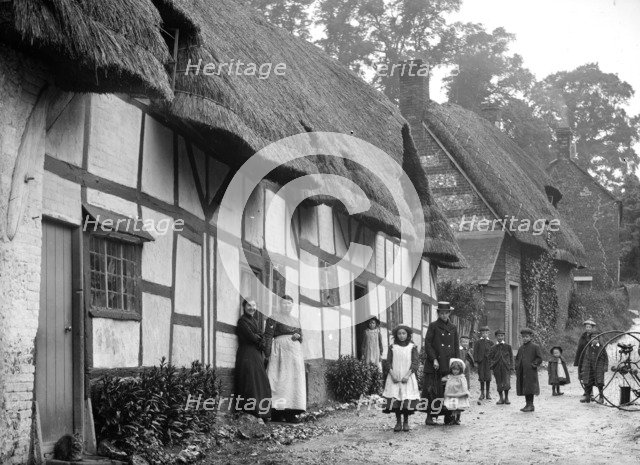 Women and children posing outside a thatched cottage, Ramsbury, Wiltshire, c1860-c1922. Artist: Henry Taunt