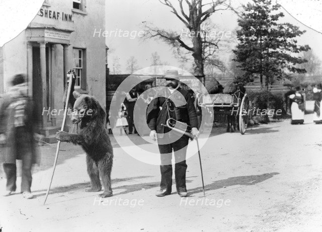 A dancing bear and owner performing outside an inn, Oxfordshire, c1900. Artist: Henry Taunt