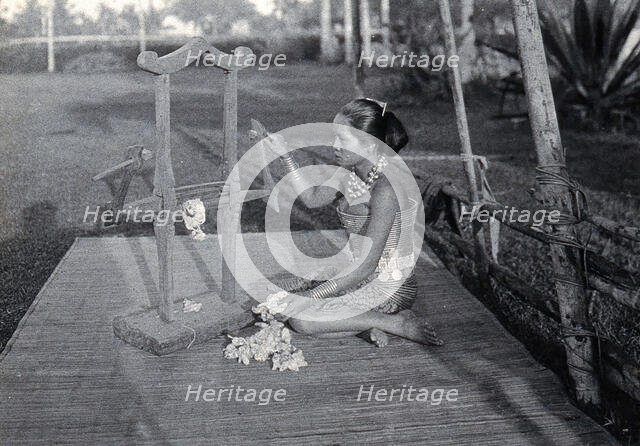 Sarawak: a girl extracting the seeds of raw cotton in a cotton gin, c1900. Creator: Unknown.