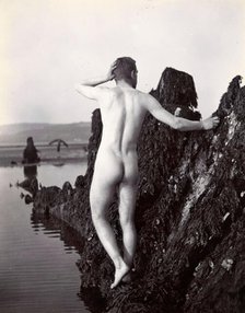 A man posing naked, with his back to the camera, standing on a rocky outcrop, c1900. Creator: Unknown.