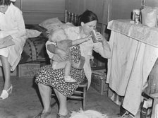 Mother from Oklahoma tends baby with dysentery, FSA camp, Tulare County, California, 1939. Creator: Dorothea Lange.
