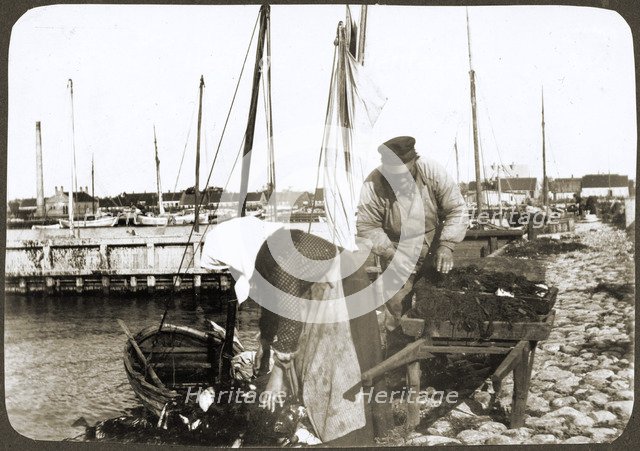 A fisherman and his wife with nets and a wheelbarrow, Borstahusen, Landskrona, Sweden, 1905. Artist: Unknown