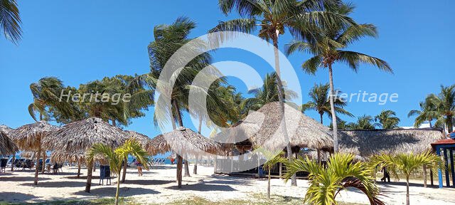 Thatched umbrellas and restaurant at the beach resort of Playa Ancon, south of Trinidad, Cuba, 2024. Creator: Ethel Davies.