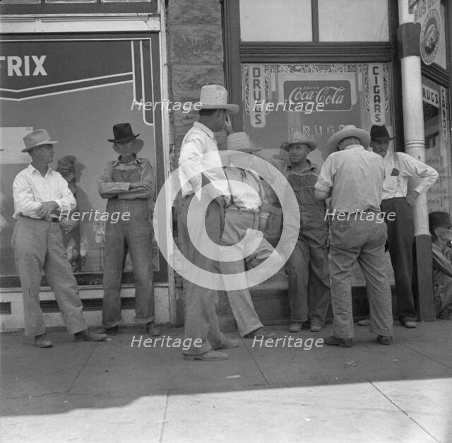 Drought farmers line the shady side of the main street of the town, Sallisaw, Oklahoma, 1936. Creator: Dorothea Lange.
