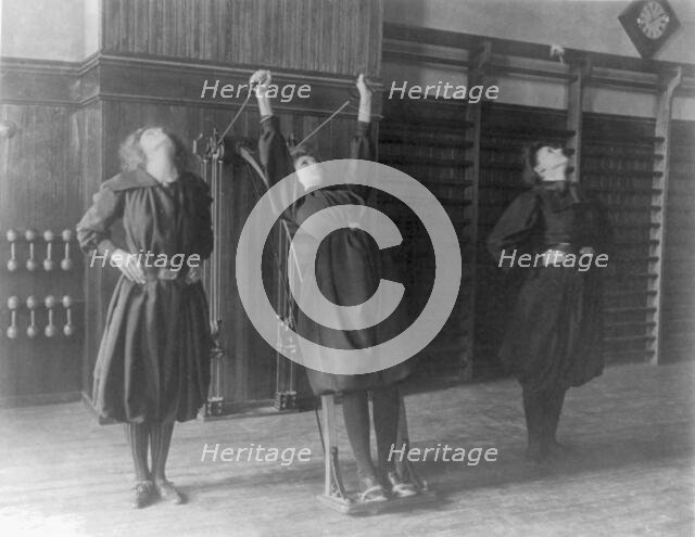Female students exercising, one with a wall-mounted device using ropes..., Washington, D.C., (1899?) Creator: Frances Benjamin Johnston.