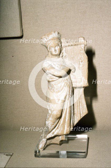 Greek Terracotta, Woman playing Kithera with plectrum, 3rd century BC-2nd century BC Artist: Unknown.