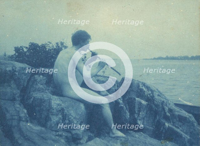 Man posed on rocks, nude, playing pipe (Pan), between 1885 and 1900. Creator: Frances Benjamin Johnston.