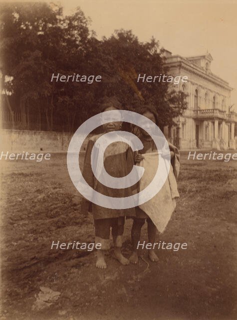 Two barefoot children standing in muddy street in front of the Lindholm's large..., (1899?). Creator: Eleanor Lord Pray.